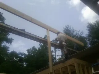 Carpenter setting a ridge beam over a new addition frame — Ice Dam Removal by Roofing Brothers in Lucas