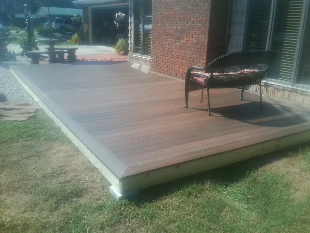 New wood deck and wicker chair beside a brick house in Lucas