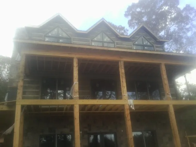 Dormers and porch framing on a large log home under construction — Roof Coating work by our crew in Lucas